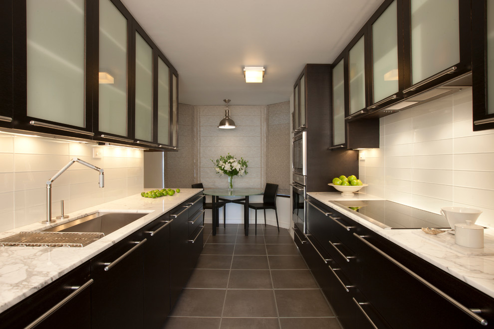 Mid-sized contemporary galley kitchen pantry in Chicago with an undermount sink, flat-panel cabinets, white splashback, glass tile splashback, stainless steel appliances, ceramic floors, no island, dark wood cabinets and marble benchtops.