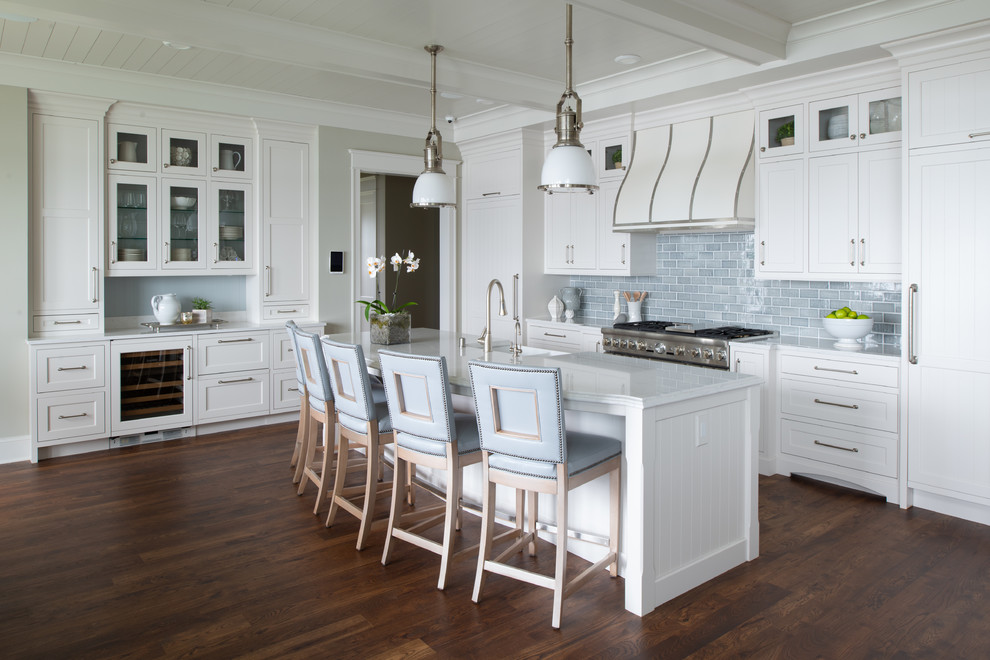 Photo of a beach style kitchen in Minneapolis with shaker cabinets, white cabinets, blue splashback, subway tile splashback, stainless steel appliances, dark hardwood floors, with island, brown floor and white benchtop.