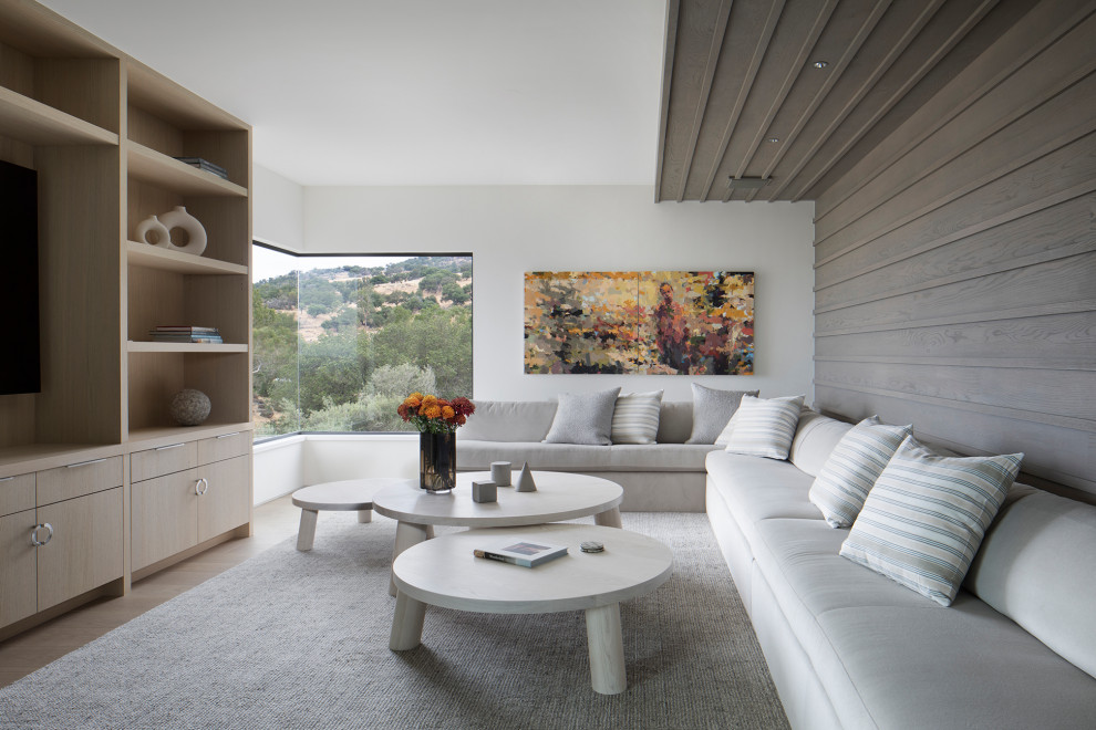 Design ideas for a modern family room in San Francisco with white walls, light hardwood floors and wood walls.