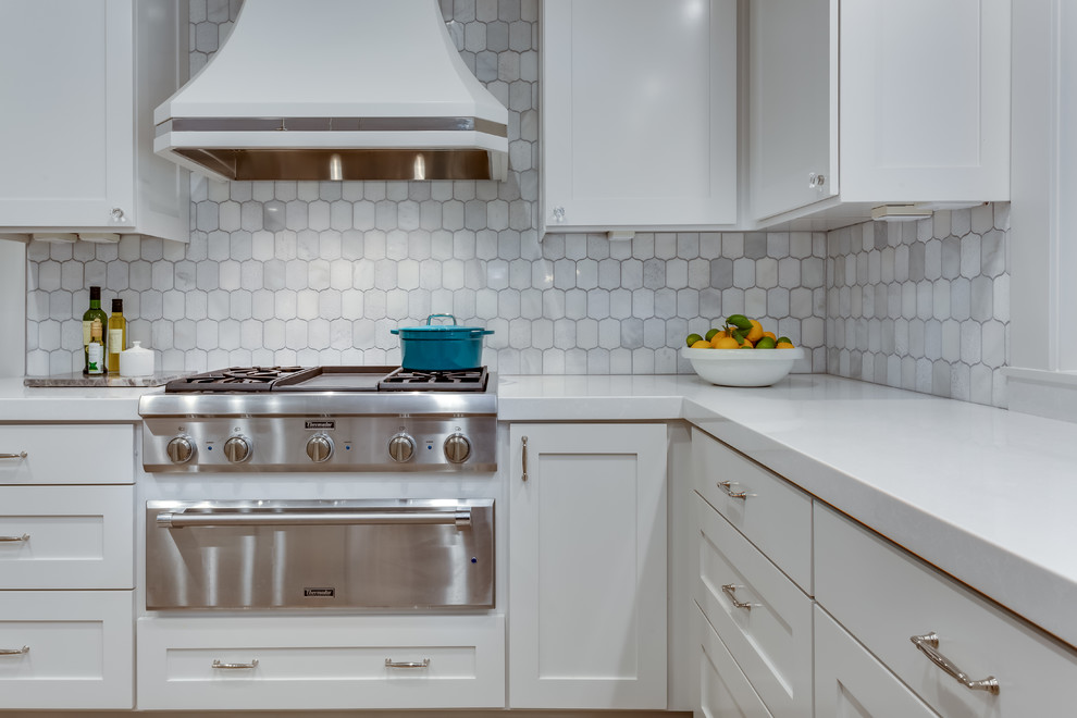 Photo of a large contemporary u-shaped separate kitchen in Sacramento with a farmhouse sink, shaker cabinets, white cabinets, solid surface benchtops, white splashback, marble splashback, stainless steel appliances, medium hardwood floors, with island, brown floor and white benchtop.
