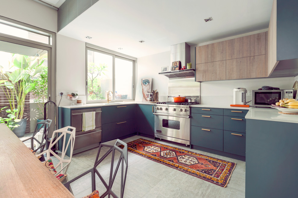 Mid-sized beach style u-shaped eat-in kitchen in Singapore with no island, an undermount sink, flat-panel cabinets, light wood cabinets, stainless steel appliances and white splashback.