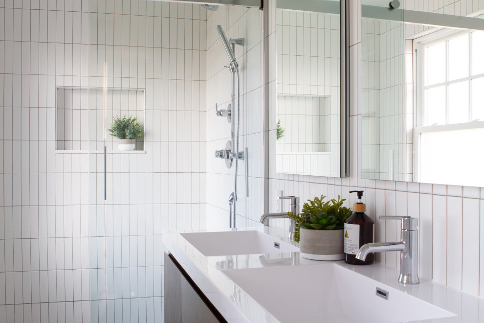 Inspiration for a modern white tile double-sink alcove shower remodel in New York with flat-panel cabinets, dark wood cabinets, an integrated sink, white countertops and a niche