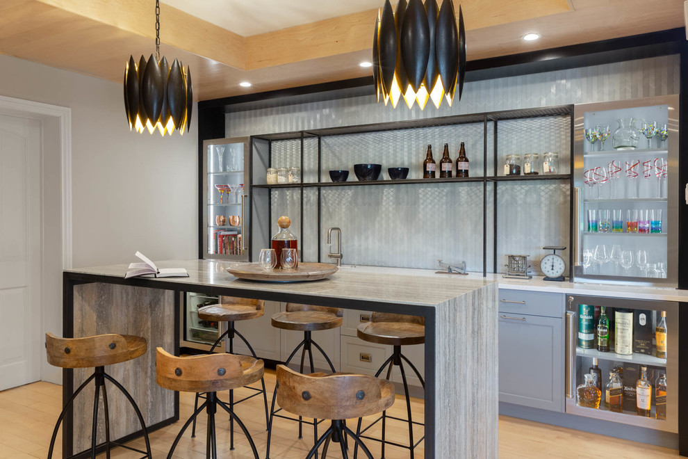 Photo of a large modern single-wall seated home bar in Other with recessed-panel cabinets, grey benchtop, an undermount sink, light hardwood floors, brown floor, grey cabinets, grey splashback and glass tile splashback.
