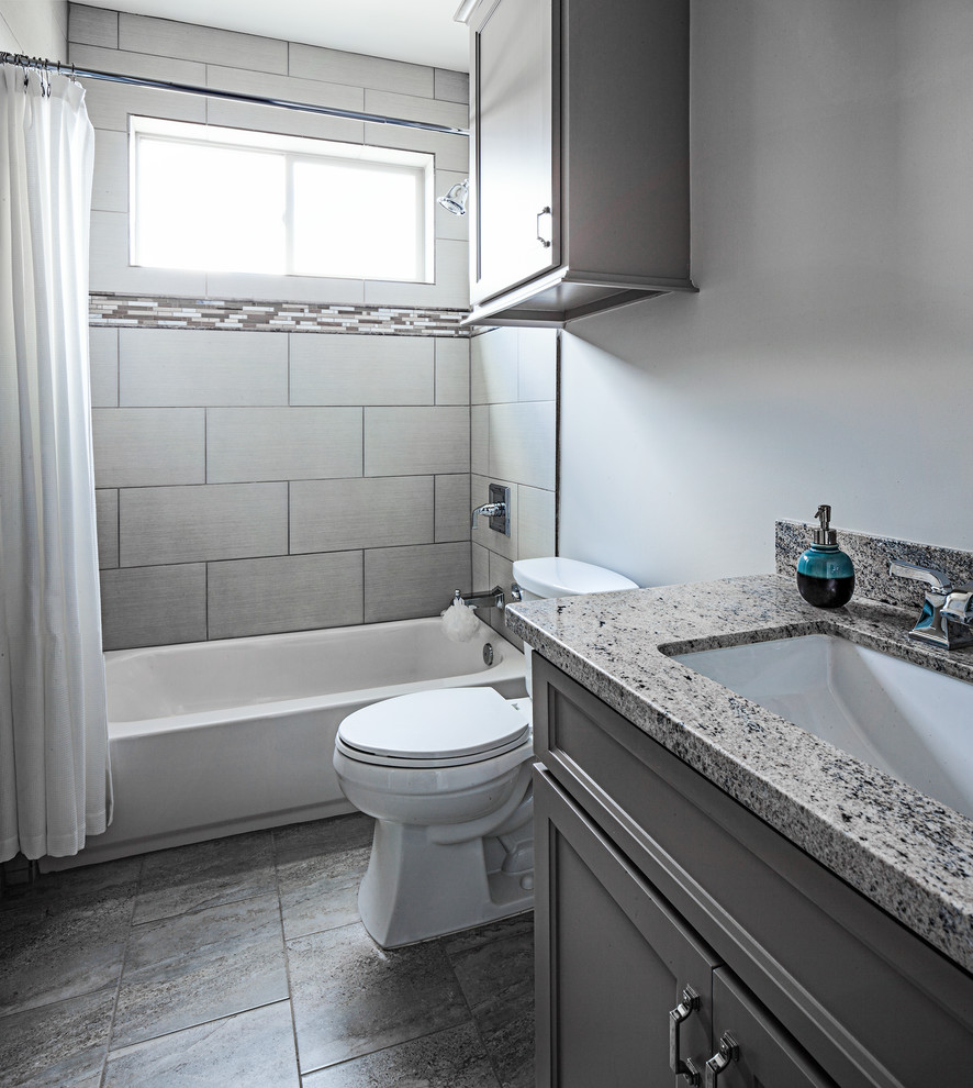 Inspiration for a small transitional master gray tile and ceramic tile ceramic tile drop-in bathtub remodel in Houston with shaker cabinets, gray cabinets, a two-piece toilet, beige walls, an undermount sink and granite countertops