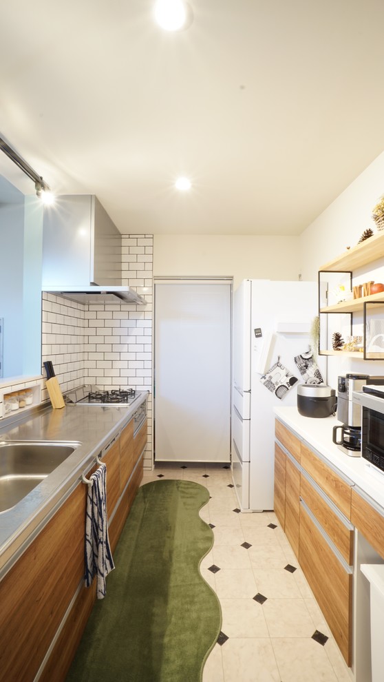 Scandinavian single-wall kitchen in Other with a single-bowl sink, flat-panel cabinets, medium wood cabinets, stainless steel benchtops, white splashback, subway tile splashback, a peninsula, multi-coloured floor and white benchtop.
