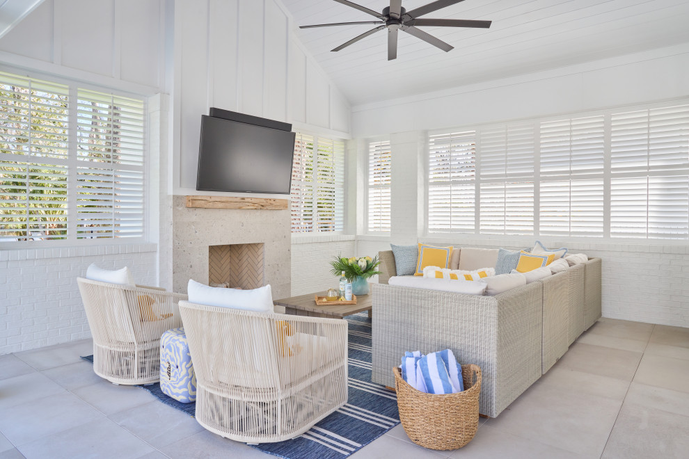 2 Chicks Happy Family Home - Outdoor covered lanai with Fireplace. A bright, family-friendly outdoor covered living area in a custom Ponte Vedra Beach new build by 2 Chicks Design Co. Woven sectional, a navy-and-white striped outdoor rug, woven basket for towels, swivel chairs, and an oversized ceiling fan create a relaxed coastal transitional living space designed for everyday gathering. Yellow and blue accents tie into the nearby hard finishes and add to the fun, coastal, resort feel.
Tags: Beach Style, Transitional, Coastal Living Room, Shiplap, Family Room, White Slipcovered Sofa, Striped Rug including large seating area, fireplace, and tv. Coastal, comfortable vibes. Yellow and Blue decor. Shutters for privacy, light control, rain control. Indoor / Outdoor Living.