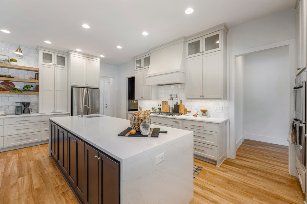 Kitchen - mid-sized transitional u-shaped light wood floor kitchen idea in Dallas with a farmhouse sink, shaker cabinets, gray cabinets, quartz countertops, white backsplash, porcelain backsplash, stainless steel appliances, two islands and white countertops