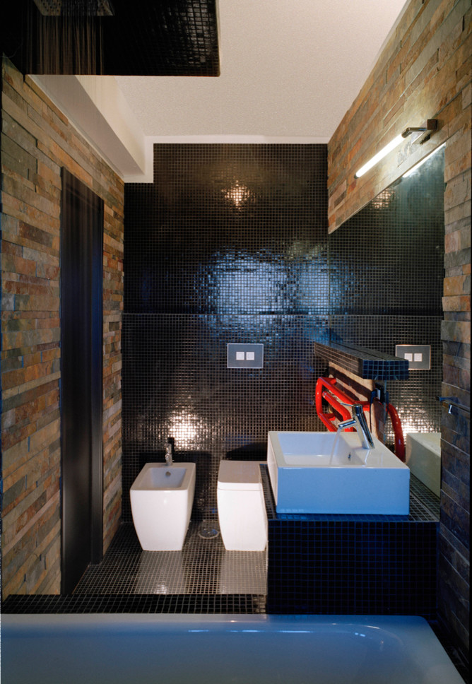 Inspiration for a small contemporary 3/4 bathroom in Rome with flat-panel cabinets, a drop-in tub, a shower/bathtub combo, a two-piece toilet, black tile, ceramic tile, black walls, ceramic floors, a drop-in sink, tile benchtops, black floor and an open shower.