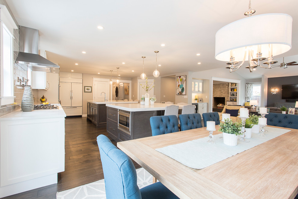 Large transitional l-shaped medium tone wood floor and brown floor eat-in kitchen photo in Denver with a single-bowl sink, recessed-panel cabinets, white cabinets, quartz countertops, gray backsplash, ceramic backsplash, stainless steel appliances and two islands