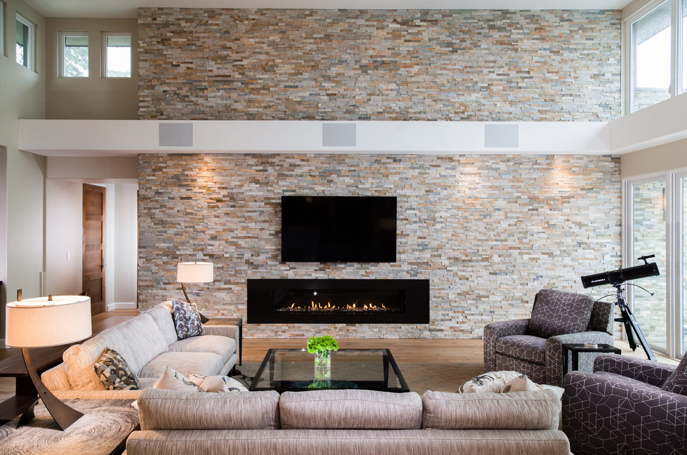 This is an example of an expansive modern open concept living room in San Francisco with beige walls, light hardwood floors, a ribbon fireplace, a stone fireplace surround and a wall-mounted tv.