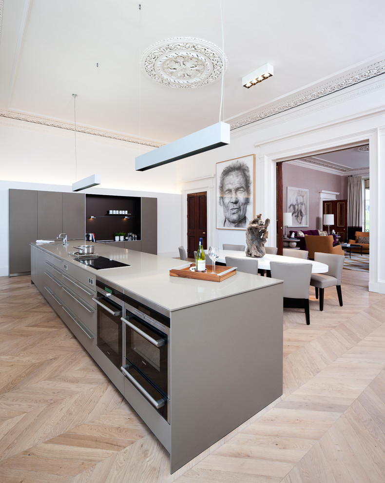This is an example of a large contemporary eat-in kitchen in Edinburgh with flat-panel cabinets, grey cabinets, light hardwood floors and with island.
