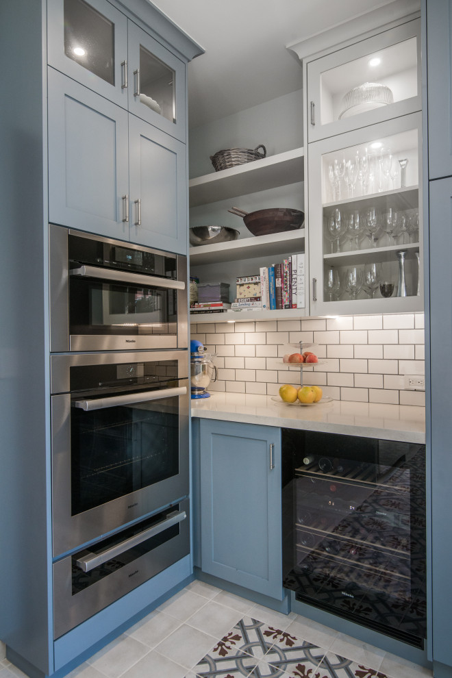 Mid-sized transitional u-shaped separate kitchen with an undermount sink, shaker cabinets, blue cabinets, limestone benchtops, white splashback, subway tile splashback, stainless steel appliances, ceramic floors, a peninsula, multi-coloured floor and white benchtop.