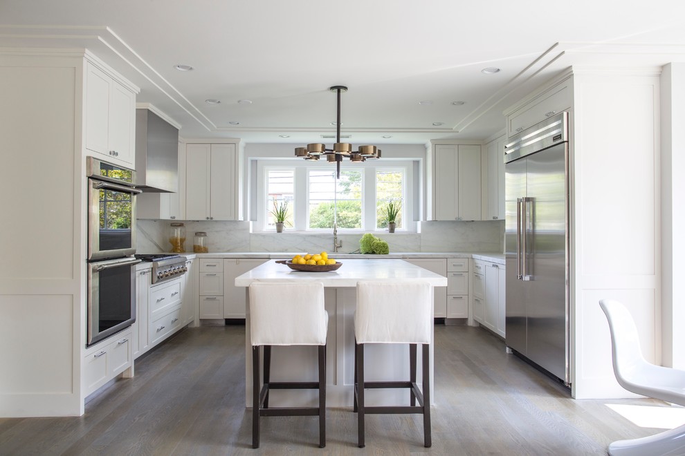 Design ideas for a transitional u-shaped eat-in kitchen in New York with shaker cabinets, white cabinets, white splashback, stone slab splashback, stainless steel appliances, light hardwood floors and with island.