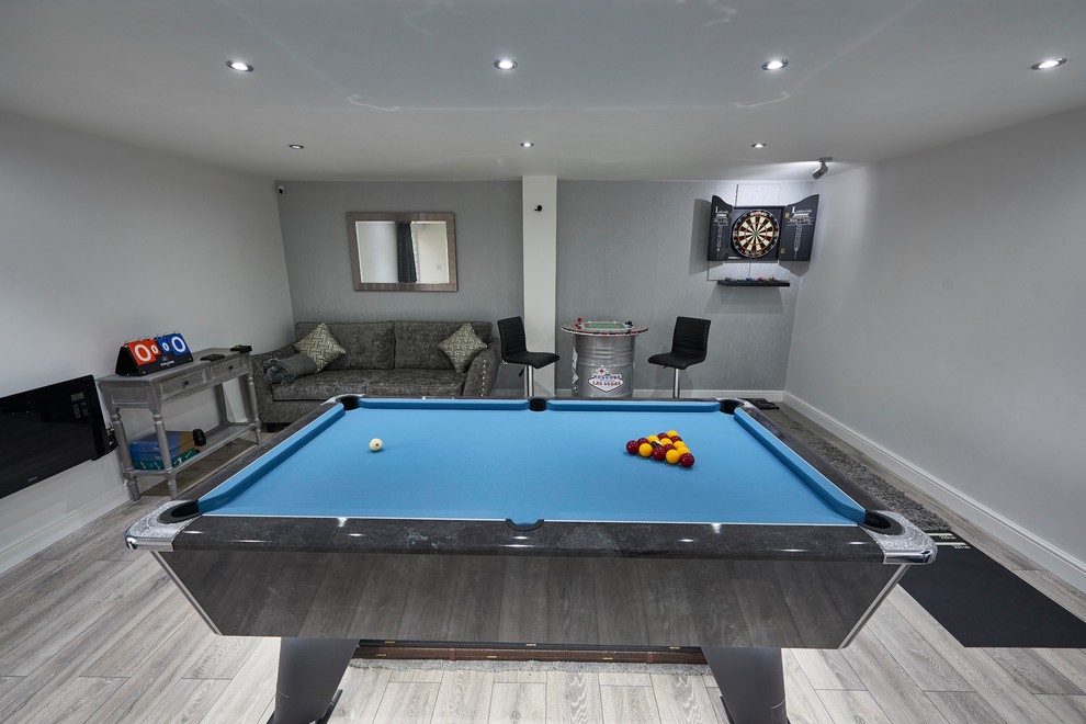 Inspiration for a small modern enclosed games room with a game room, grey walls, laminate floors, a wall mounted tv and grey floors.