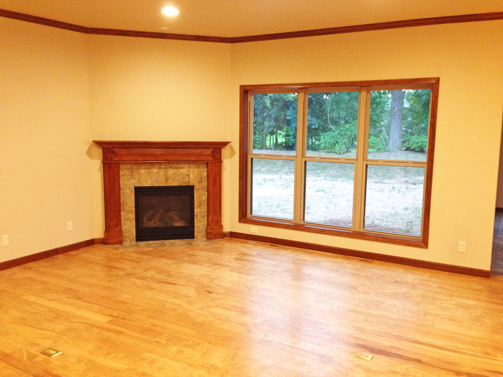 Inspiration for a mid-sized traditional open concept living room in Milwaukee with beige walls, light hardwood floors, a corner fireplace, a wood fireplace surround and no tv.