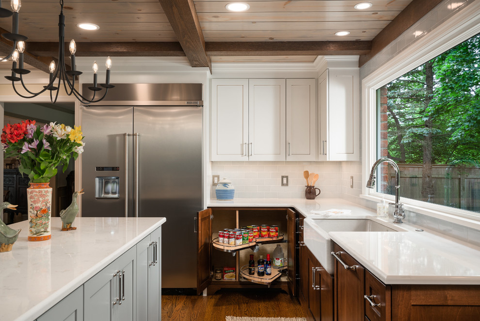 Inspiration for a mid-sized transitional galley medium tone wood floor and brown floor eat-in kitchen remodel in Columbus with a farmhouse sink, shaker cabinets, dark wood cabinets, quartz countertops, white backsplash, subway tile backsplash, stainless steel appliances, an island and white countertops