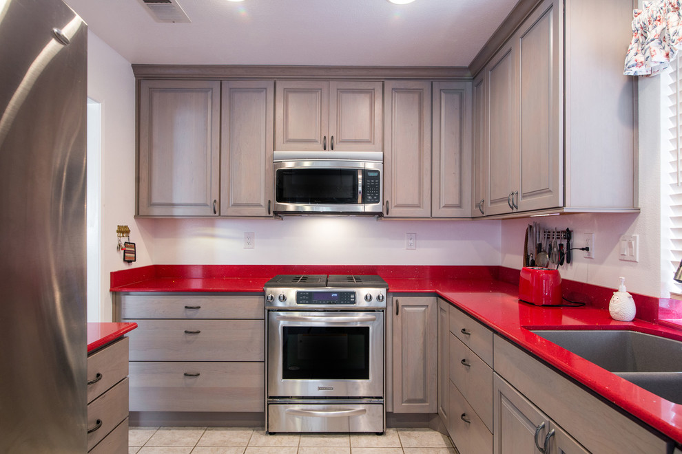 This is an example of a small modern u-shaped eat-in kitchen in San Diego with an undermount sink, raised-panel cabinets, grey cabinets, quartz benchtops, stainless steel appliances, ceramic floors, no island and red benchtop.
