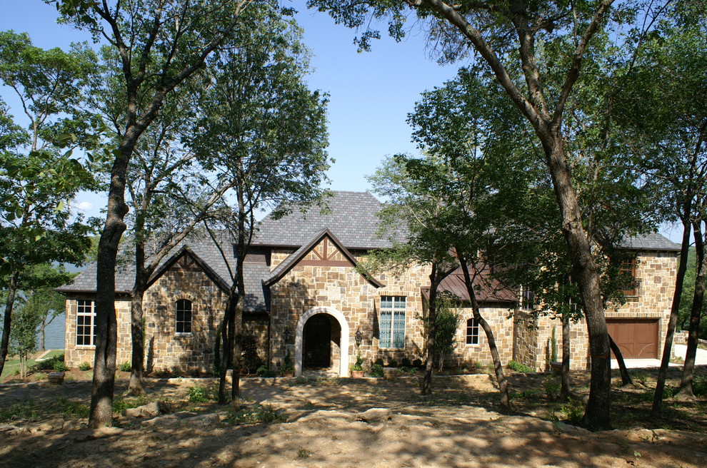 Photo of a large traditional two-storey beige exterior in Dallas with stone veneer and a hip roof.
