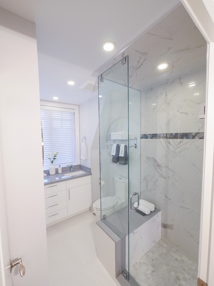 Design ideas for a mid-sized contemporary 3/4 bathroom in Toronto with flat-panel cabinets, white cabinets, a corner shower, a one-piece toilet, gray tile, white tile, marble, white walls, porcelain floors, an undermount sink, engineered quartz benchtops, white floor and a hinged shower door.