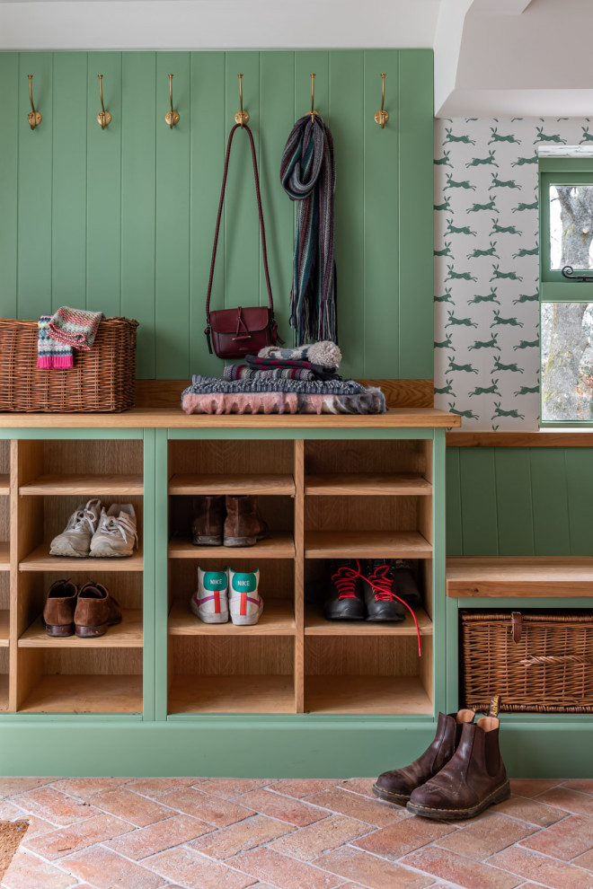 Photo of a country mudroom in Surrey with green walls, brick floors, red floor, planked wall panelling and wallpaper.
