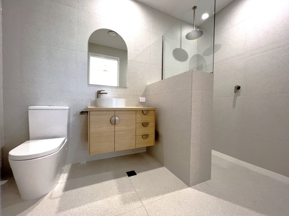 На фото: ванная комната в современном стиле с плоскими фасадами, светлыми деревянными фасадами, открытым душем, унитазом-моноблоком, серой плиткой, керамической плиткой, серыми стенами, полом из керамической плитки, столешницей из ламината, серым полом, открытым душем, нишей, тумбой под одну раковину и подвесной тумбой