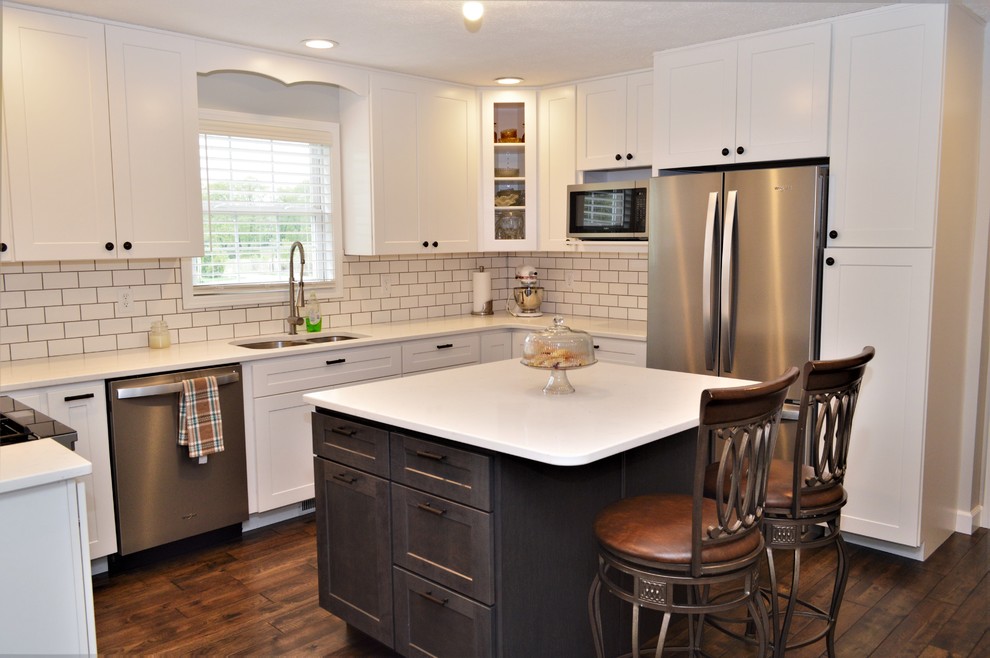 This is an example of a mid-sized transitional u-shaped eat-in kitchen in Chicago with an undermount sink, shaker cabinets, white cabinets, quartzite benchtops, white splashback, subway tile splashback, stainless steel appliances, medium hardwood floors, with island, brown floor and white benchtop.