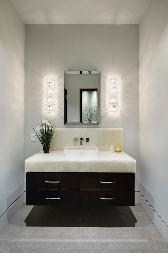 Inspiration for a small transitional powder room in Vancouver with flat-panel cabinets, black cabinets, white walls, porcelain floors, a vessel sink, onyx benchtops, grey floor and white benchtops.