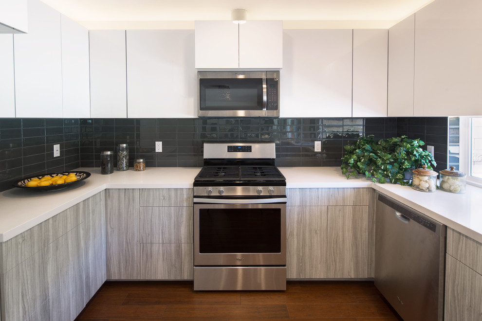 This is an example of a mid-sized contemporary u-shaped eat-in kitchen in Los Angeles with an undermount sink, flat-panel cabinets, white cabinets, quartz benchtops, grey splashback, porcelain splashback, stainless steel appliances, dark hardwood floors, a peninsula and brown floor.