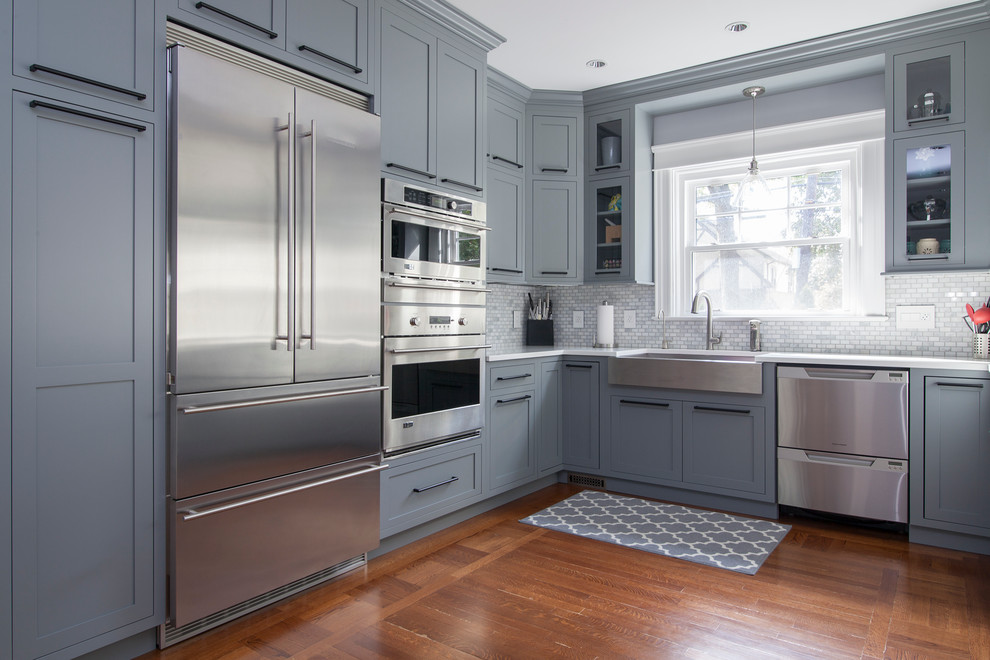 Design ideas for a large transitional u-shaped eat-in kitchen in New York with a farmhouse sink, shaker cabinets, grey cabinets, stone tile splashback, stainless steel appliances, medium hardwood floors and a peninsula.