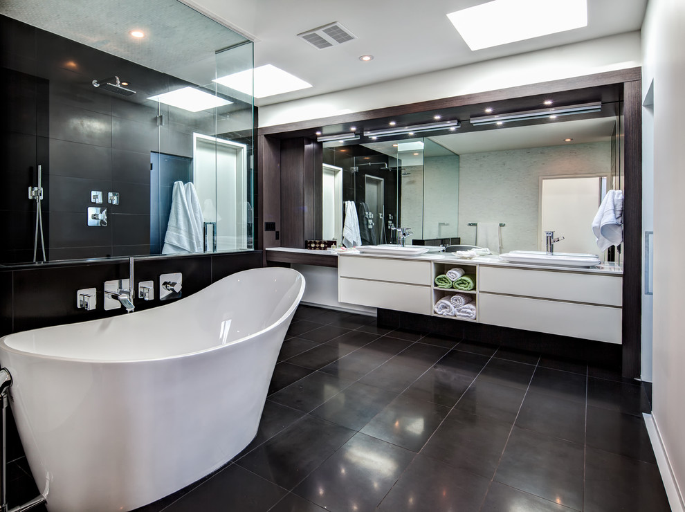 Photo of a large contemporary master bathroom in Calgary with a vessel sink, flat-panel cabinets, white cabinets, a freestanding tub, a corner shower, black tile, quartzite benchtops, a bidet, stone tile, white walls, ceramic floors and black floor.