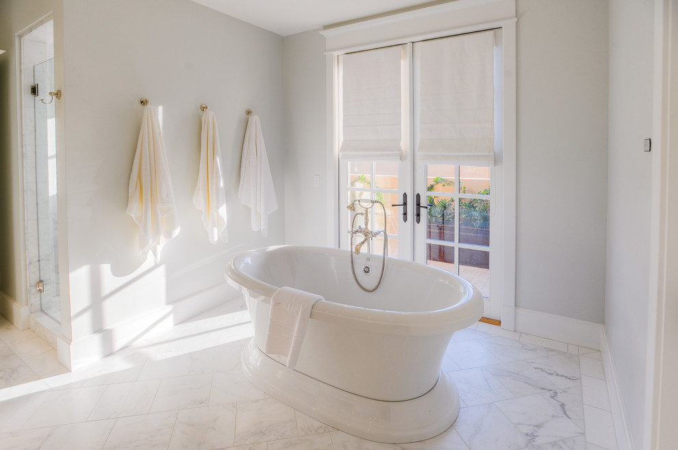 Inspiration for a transitional bathroom in Phoenix with an undermount sink, furniture-like cabinets, white cabinets, marble benchtops, a freestanding tub, white tile and stone tile.