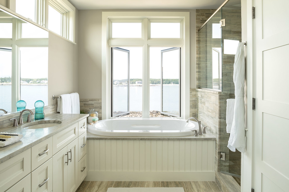 Design ideas for a beach style master bathroom in Portland Maine with a drop-in tub, recessed-panel cabinets, white cabinets, an alcove shower, multi-coloured tile, ceramic tile, an undermount sink, a hinged shower door, grey benchtops, a single vanity and a floating vanity.