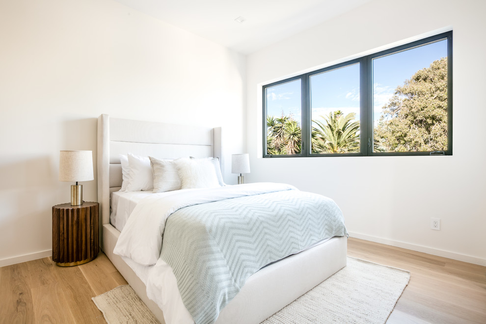 This is an example of a contemporary guest bedroom in Los Angeles with white walls and light hardwood floors.