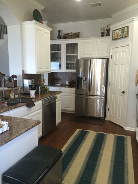 Example of a mid-sized transitional l-shaped dark wood floor enclosed kitchen design in Austin with a drop-in sink, raised-panel cabinets, white cabinets, granite countertops, brown backsplash, porcelain backsplash, stainless steel appliances and no island