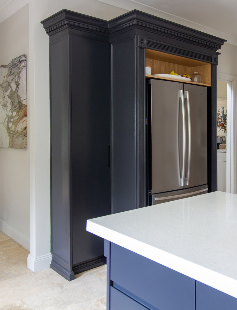 Inspiration for a mid-sized beach style u-shaped eat-in kitchen in Sydney with a double-bowl sink, flat-panel cabinets, black cabinets, quartz benchtops, beige splashback, marble splashback, stainless steel appliances, travertine floors, with island, beige floor and white benchtop.