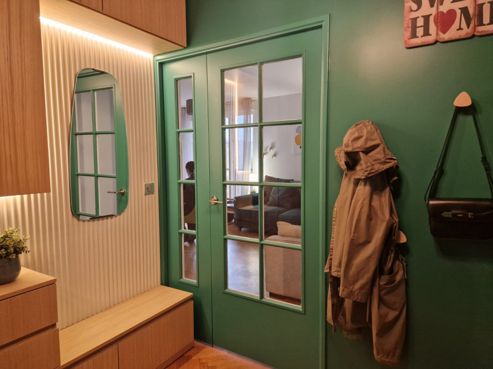 This is an example of a small contemporary foyer in Paris with green walls, light hardwood flooring, a double front door, a green front door, beige floors and wood walls.