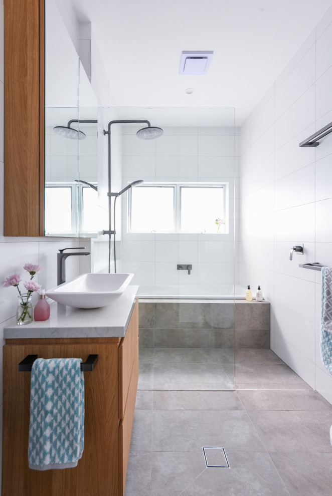 Inspiration for a mid-sized contemporary master wet room bathroom in Sydney with flat-panel cabinets, medium wood cabinets, a drop-in tub, white tile, ceramic tile, ceramic floors, engineered quartz benchtops, grey floor, an open shower, white benchtops and a vessel sink.