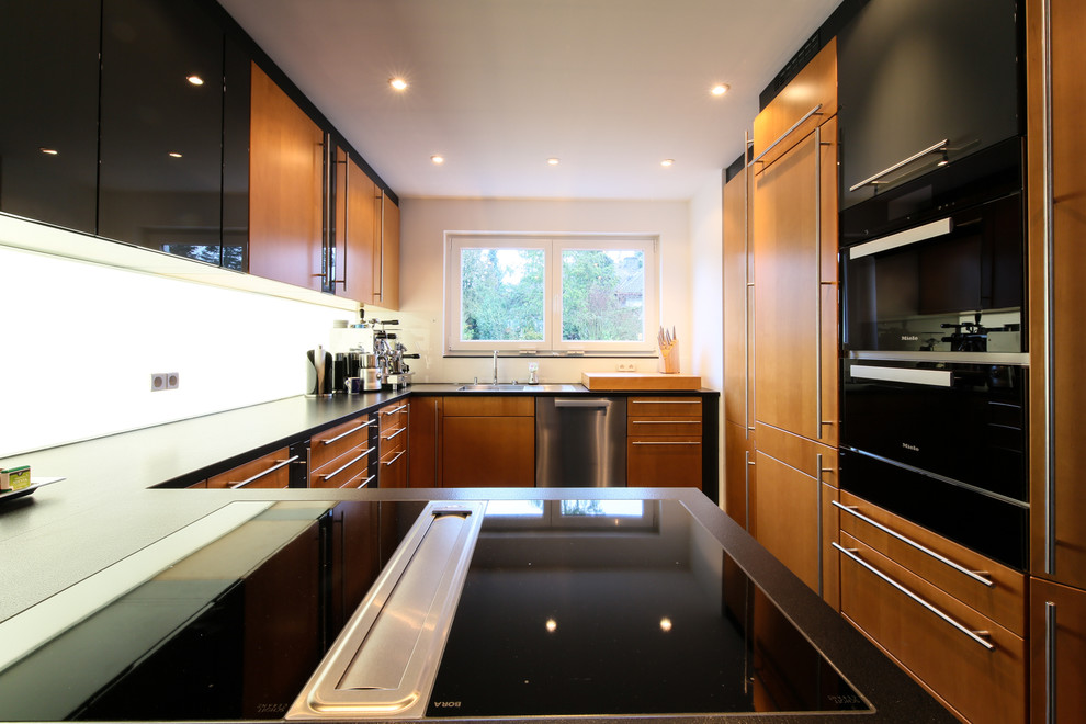 Inspiration for a contemporary kitchen in Frankfurt with glass benchtops and black appliances.
