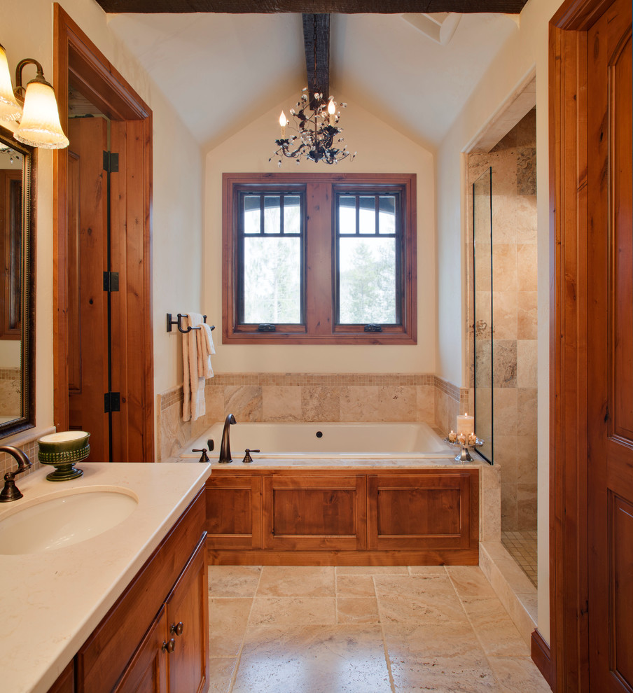 Photo of a mid-sized transitional master bathroom in Denver with recessed-panel cabinets, medium wood cabinets, a drop-in tub, an alcove shower, beige tile, beige walls, an undermount sink, engineered quartz benchtops, an open shower, travertine, travertine floors, beige floor and beige benchtops.