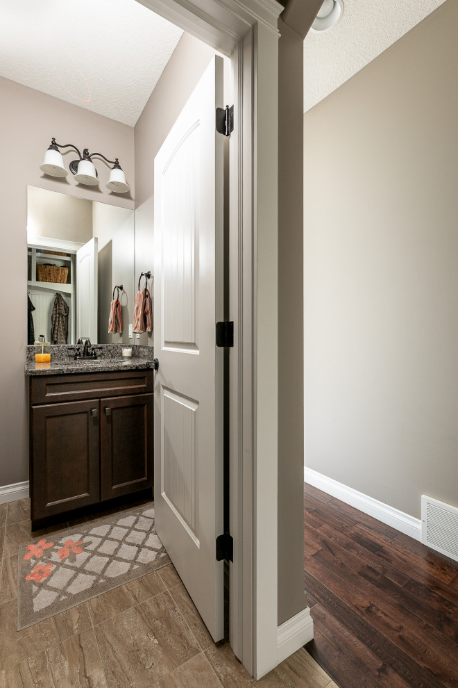 Inspiration for a mid-sized transitional l-shaped medium tone wood floor, brown floor and vaulted ceiling eat-in kitchen remodel with an undermount sink, flat-panel cabinets, white cabinets, granite countertops, beige backsplash, stone tile backsplash, stainless steel appliances, an island and beige countertops