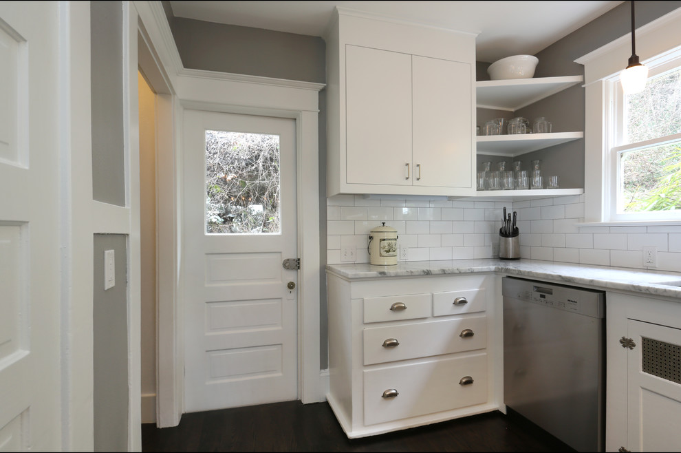 Small transitional u-shaped eat-in kitchen in Portland with an undermount sink, flat-panel cabinets, white cabinets, marble benchtops, white splashback, subway tile splashback, stainless steel appliances and dark hardwood floors.