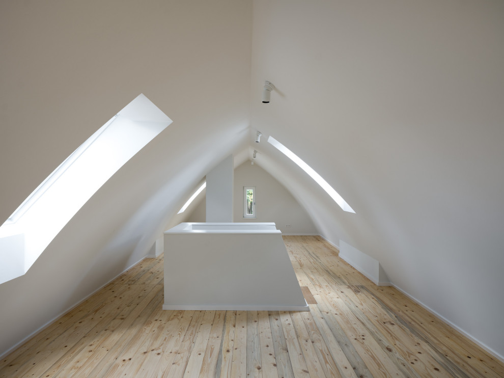 Klassischer Fitnessraum mit weißer Wandfarbe, hellem Holzboden, braunem Boden und gewölbter Decke in Hamburg
