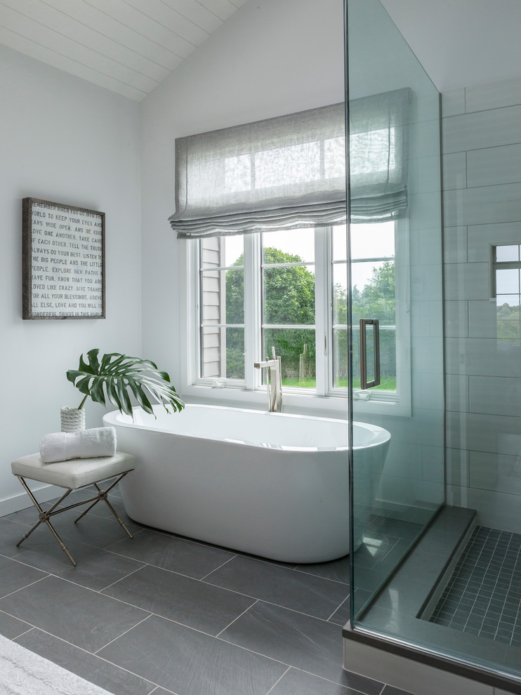 This is an example of a traditional bathroom in New York with a freestanding tub and grey floor.
