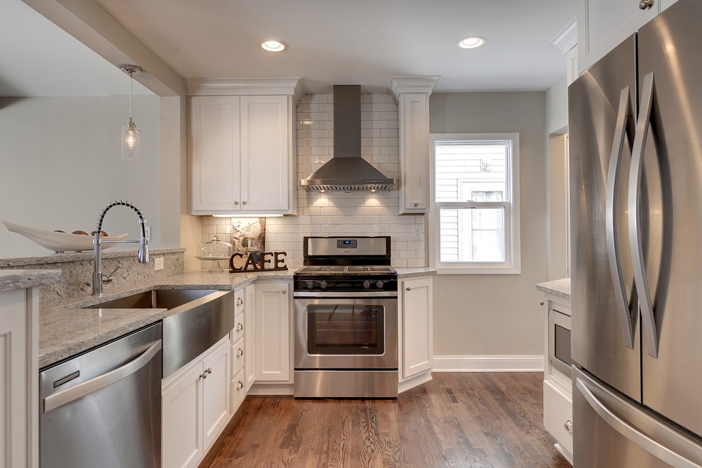 Inspiration for a small transitional l-shaped eat-in kitchen in Minneapolis with a farmhouse sink, flat-panel cabinets, white cabinets, granite benchtops, white splashback, ceramic splashback, stainless steel appliances and medium hardwood floors.
