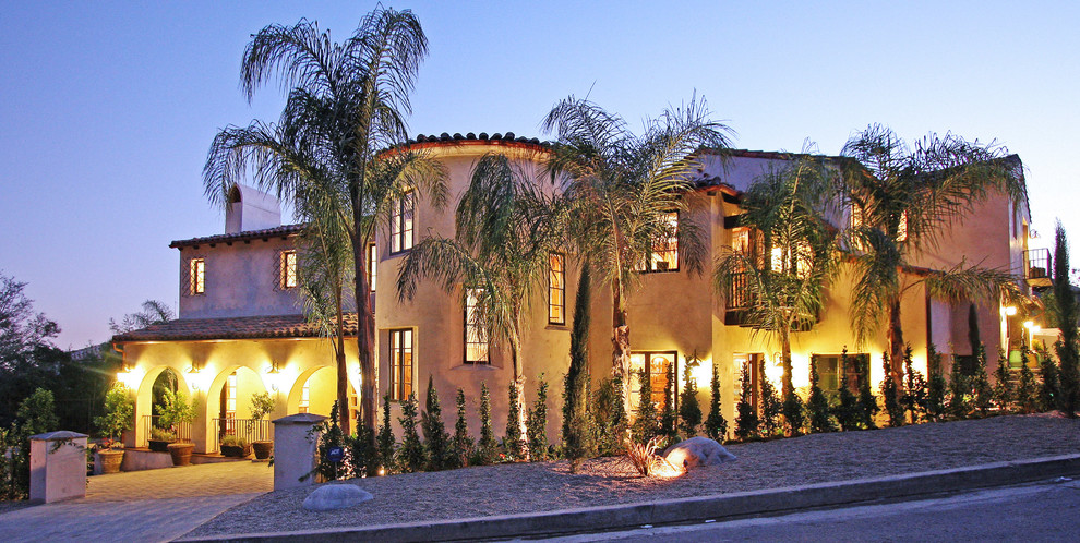 Photo of a large mediterranean two-storey stucco beige exterior in Los Angeles with a gable roof.