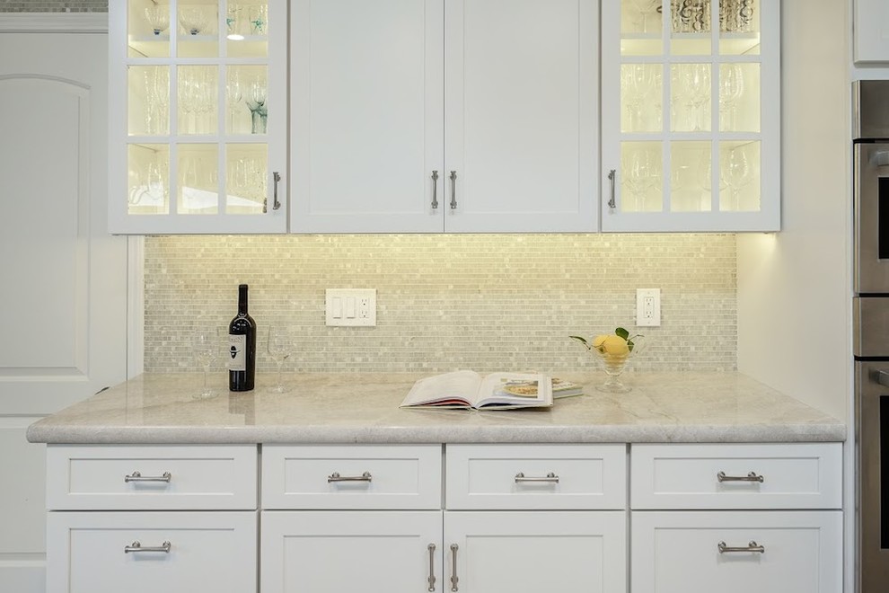 Large transitional u-shaped limestone floor eat-in kitchen photo with an undermount sink, shaker cabinets, white cabinets, marble countertops, metallic backsplash, mosaic tile backsplash, stainless steel appliances and an island
