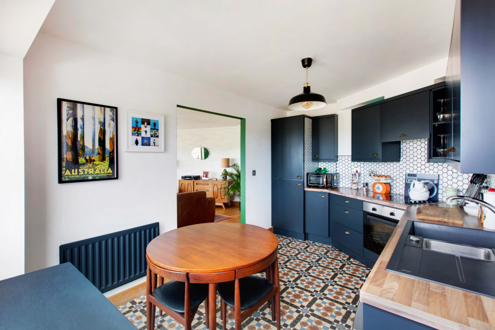 Inspiration for a contemporary eat-in kitchen in Dublin with an integrated sink, flat-panel cabinets, wood benchtops, white splashback, panelled appliances, ceramic floors and multi-coloured floor.