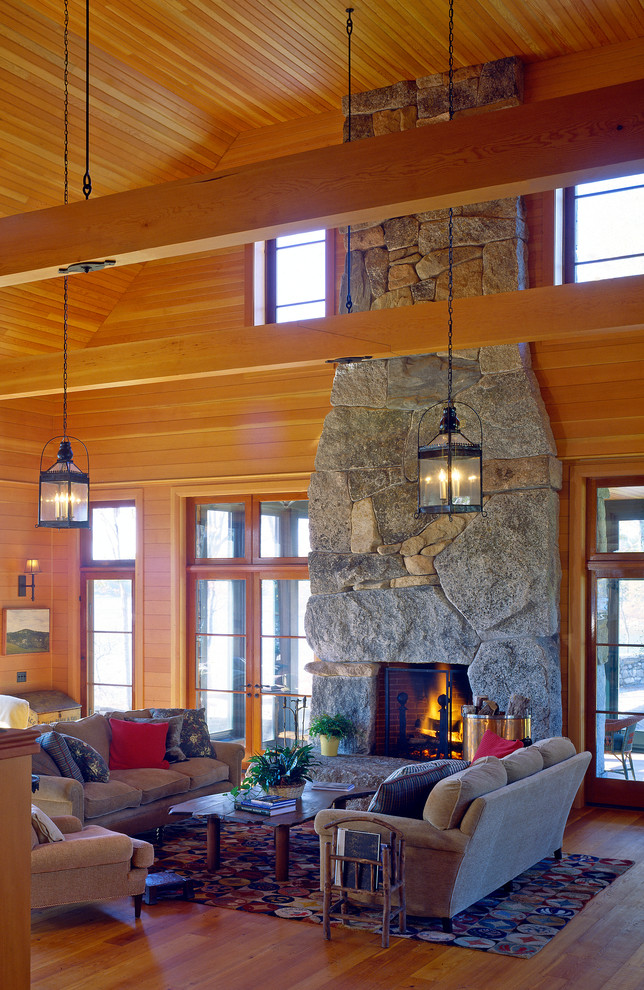This is an example of a large country enclosed family room in Other with multi-coloured walls, medium hardwood floors, a standard fireplace, a stone fireplace surround and no tv.