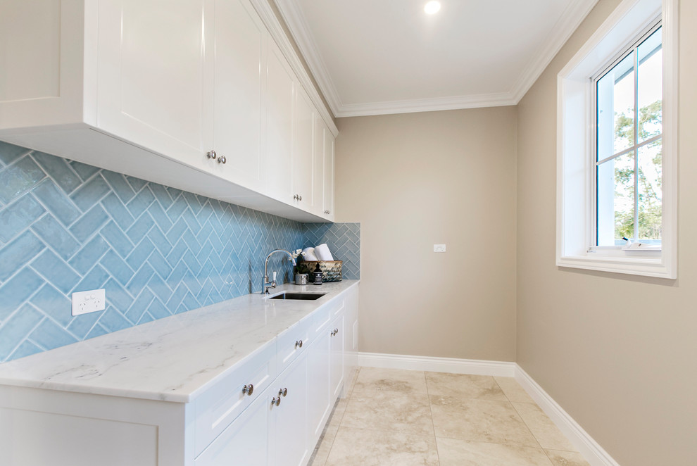 Design ideas for a mid-sized transitional single-wall dedicated laundry room in Gold Coast - Tweed with an undermount sink, shaker cabinets, white cabinets, marble benchtops, beige walls, marble floors, a concealed washer and dryer and beige floor.
