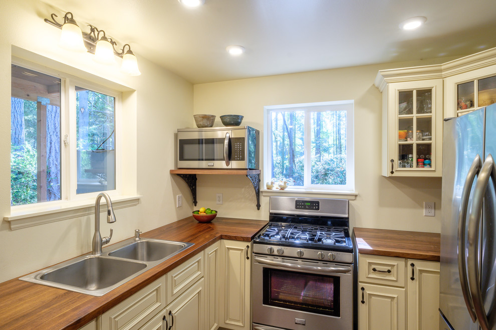 Small country u-shaped kitchen in Seattle with raised-panel cabinets, wood benchtops, dark hardwood floors and brown floor.